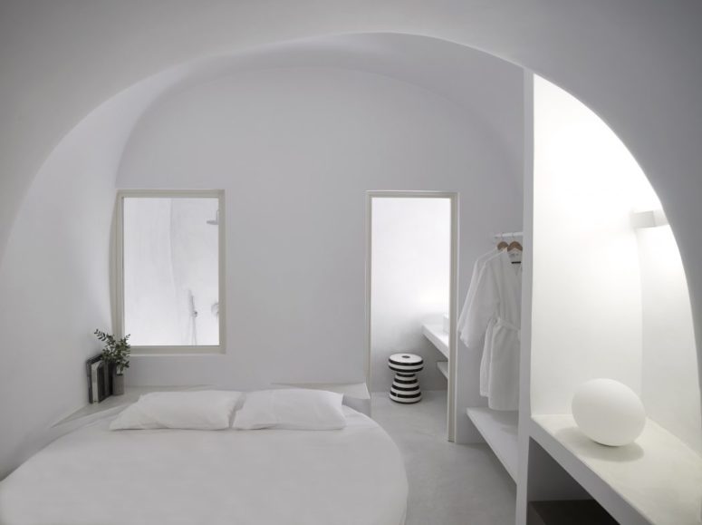 One of the bedrooms with a round bed, some built-in shelves and a bathroom enclosed