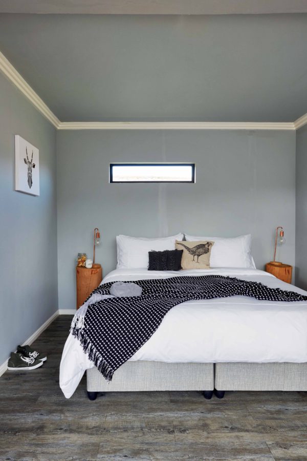 bold reclaimed floor The bedroom is small and simple, with a reclaimed wood floor, blue walls and ceiling and wooden stump nightstands with bulbs