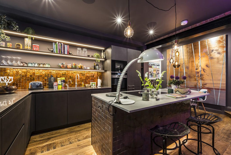 The kitchen is an artistic space with shiny gold tiles, a large tiled kitchen island and dark grey furniture