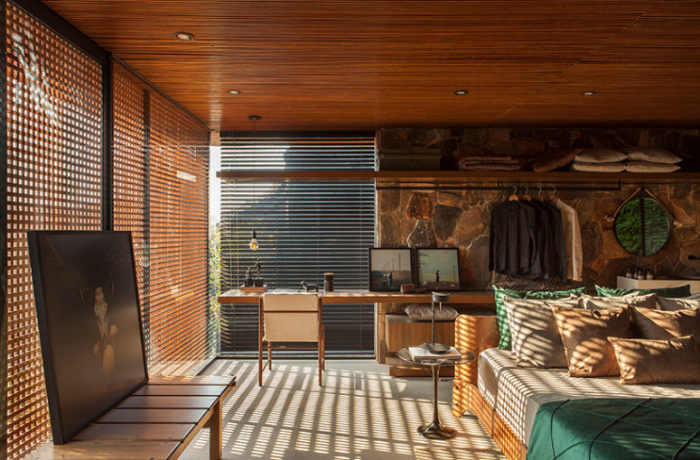 The master bedroom is done with wooden screens, stone, wood and leather and there's an open storage space