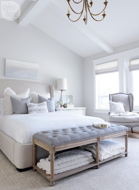 a grey upholstered vintage bench with a storage space for towels perfectly fits an airy bedroom