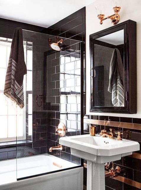 black glossy tiles with brass details and fixtures look chic and bold, perfect for a masculine space
