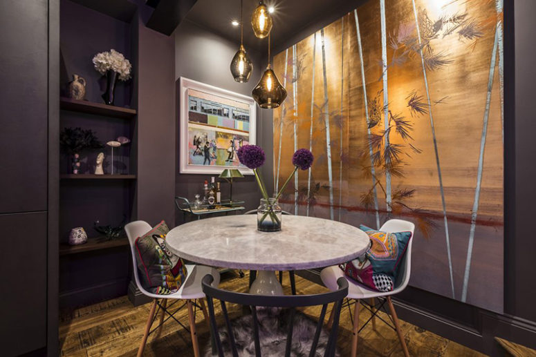 The dining space is done with a round marble table, mismatched chairs, a cool palm tree wall art and bold pillows