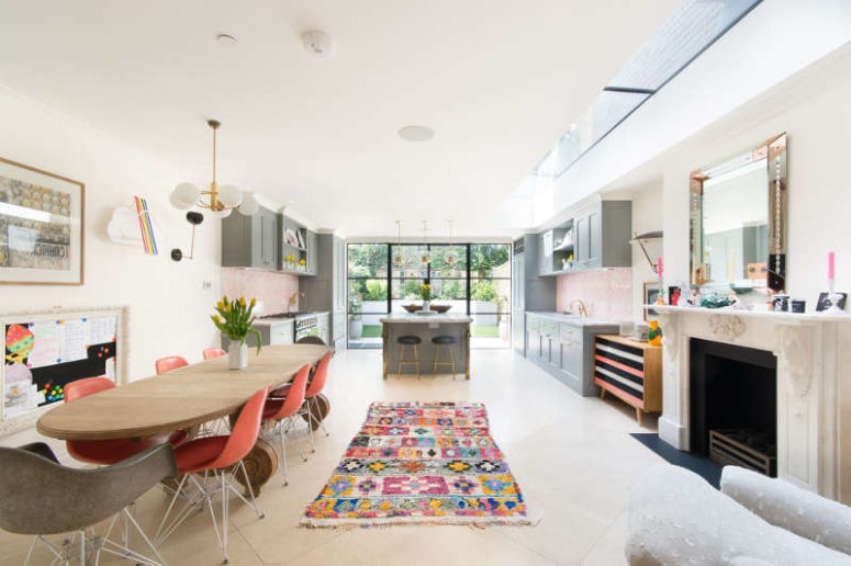 The dining space is done with colorful artworks and touches, an antique fireplace and a cool dining set, coral chairs add a cool feel to the space The dining space is done with colorful artworks and touches, an antique fireplace and a cool dining set, coral chairs add a cool feel to the space