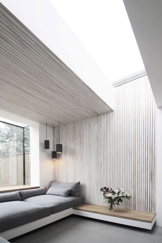 a modern space with a wall of whitewashed wood and a matching ceiling over the sofa