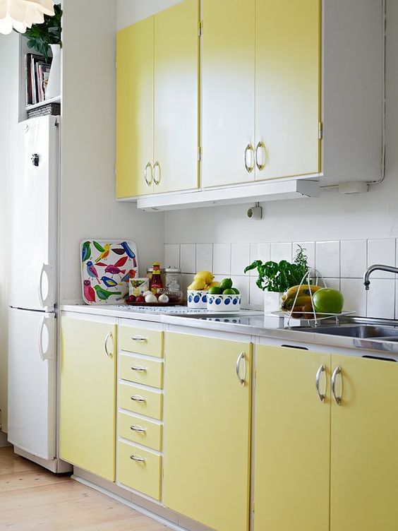 lemon yellow cabinets and a white tile backsplash look chic, colorful and warming up