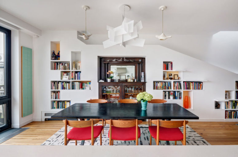 The dining space is done with a modern dining set with fuchsia chairs, a black table and a sculptural lamp
