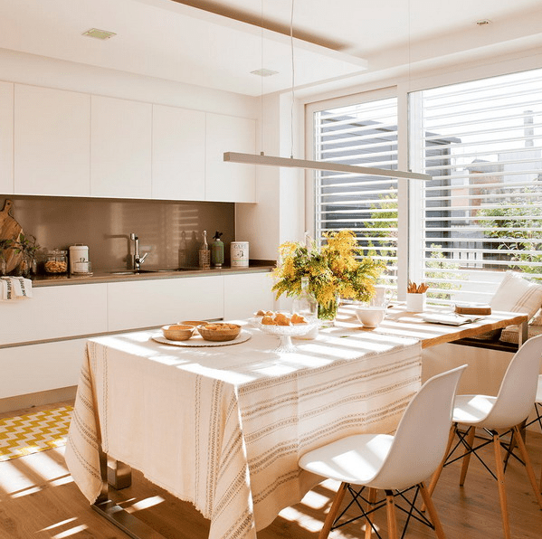 The kitchen features a sleek white kitchen with a brown backsplash, and a large window bring much light in The kitchen features a sleek white kitchen with a brown backsplash, and a large window bring much light in