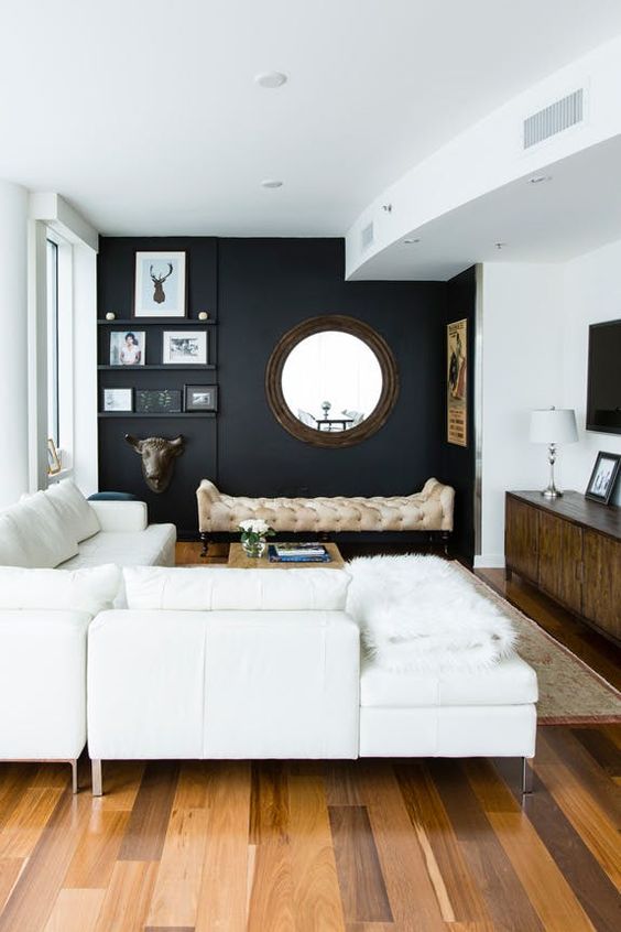 a chic modern space with a black wall, creamy furniture, walls and a ceiling and cool accessories and details