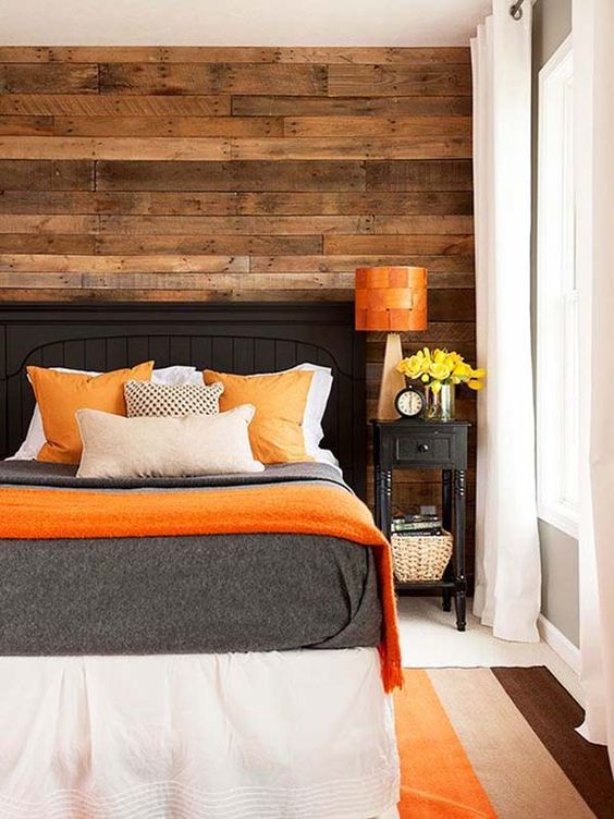 a cozy bedroom with a reclaimed wooden wall and bold orange accents that add a cheerful touch to the space