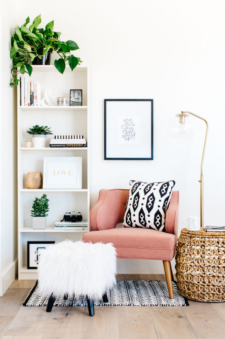 a cozy corner with a pink armchair, a floor lamp and some poufs is an ideal reading nook and is very inviting