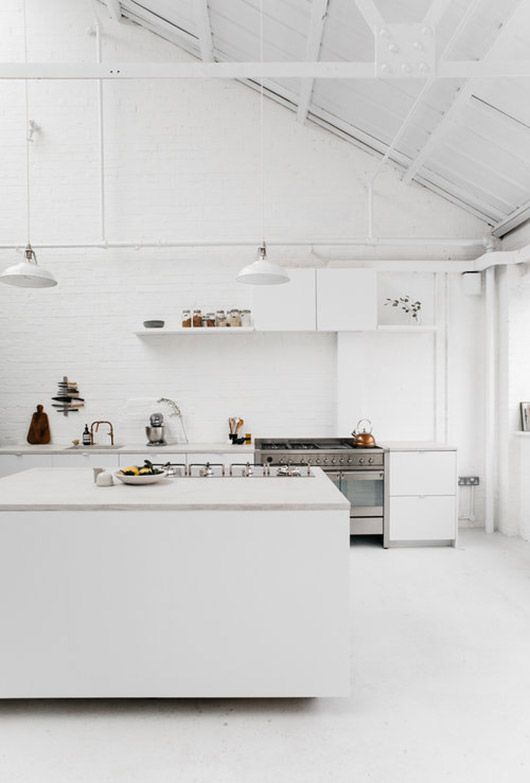 a modern whitewashed space with whitwashed brick walls and a sloped ceiling and lamps