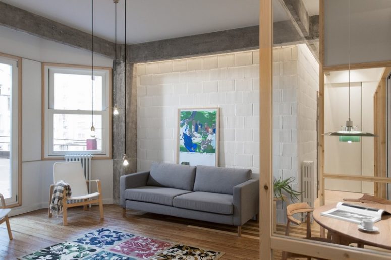 The living room features modern furniture, industrial lamps and some colorful touches like a rug and an artwork