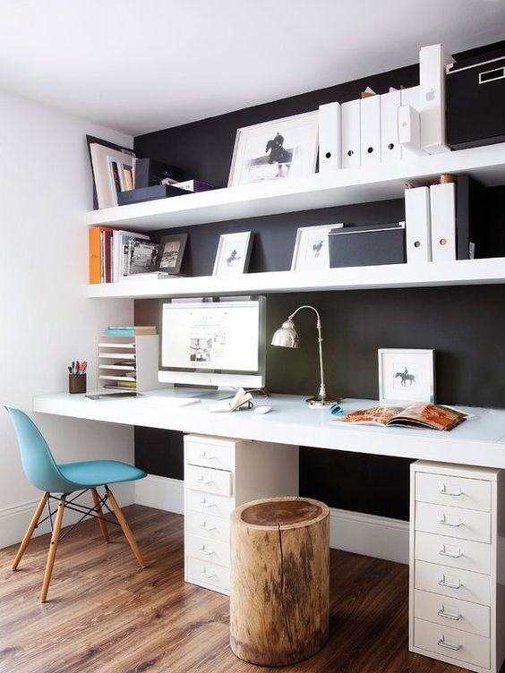 a Scandinavian home office with a black wall and white IKEA lack shelves and a white deck standing out in front of such a wall