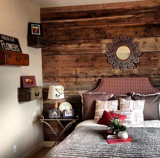 a cozy rustic bedroom with a reclaimed stained wooden wall, vintage suitcases turned into shelves
