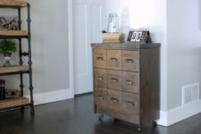 06 a small reclaimed wood apothecary cabinet placed on casters as a cute and eye-catchy entryway console