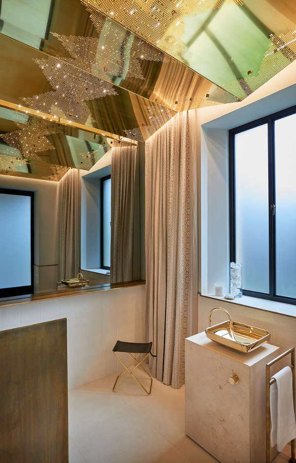The bathroom strikes with a unique gold lace ceiling that sparkles and a stunning square bowl sink on a marble vanity
