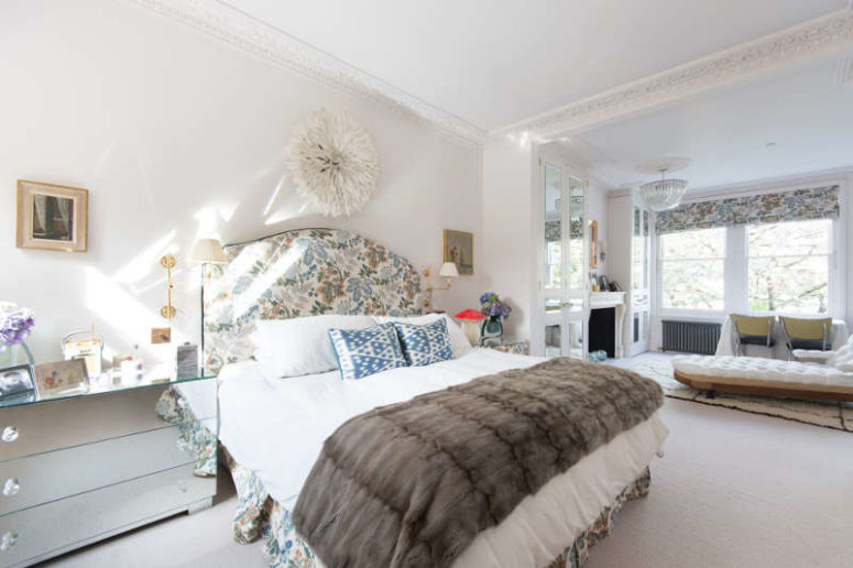 The master bedroom features floral print fabric, which is used for upholsterign the bed, curtains, furniture
