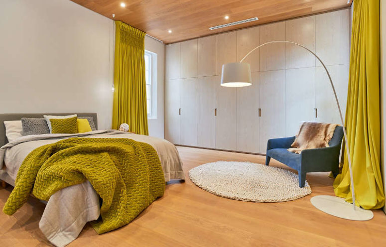 The master bedroom is done with bold pistachio touches, white cabinetry and an comfy upholstered bed