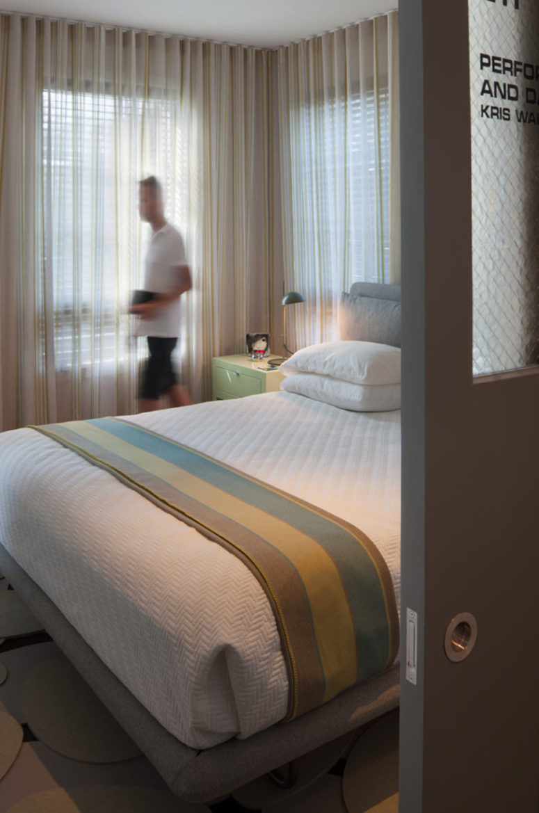 The master bedroom is done with upholstered furniture, light colored curtains and pastel nightstands The master bedroom is done with upholstered furniture, light-colored curtains and pastel nightstands