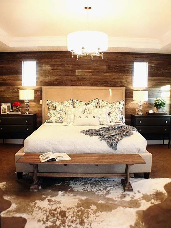 a gorgeous wooden wall, an animal skin rug and an upholstered bed add textures to the space