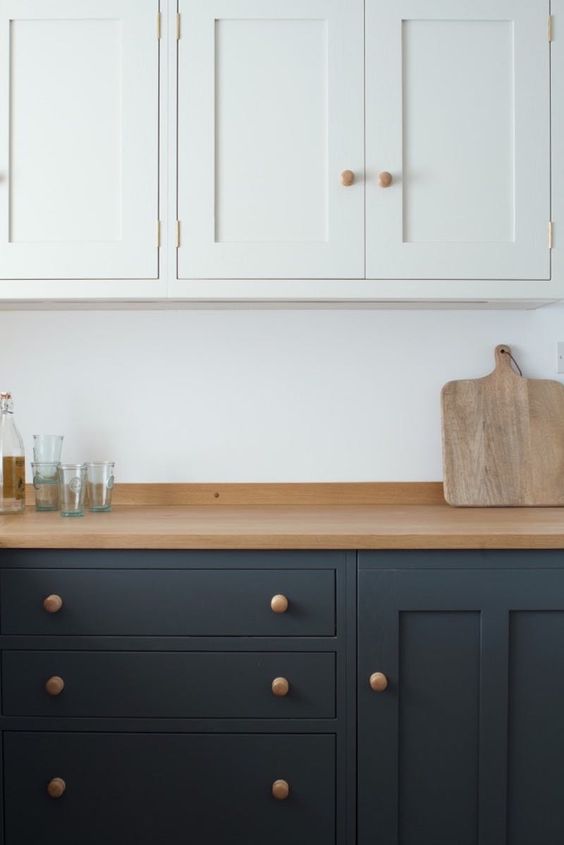 a graphite grey and white modern kitchen is softened with light-colored wood - a countertop and knobs