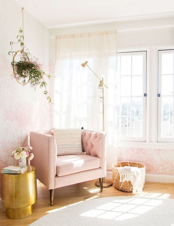 a nook by the wall taken by a pink chair, a floor lamp and a brass side table as a glam reading space