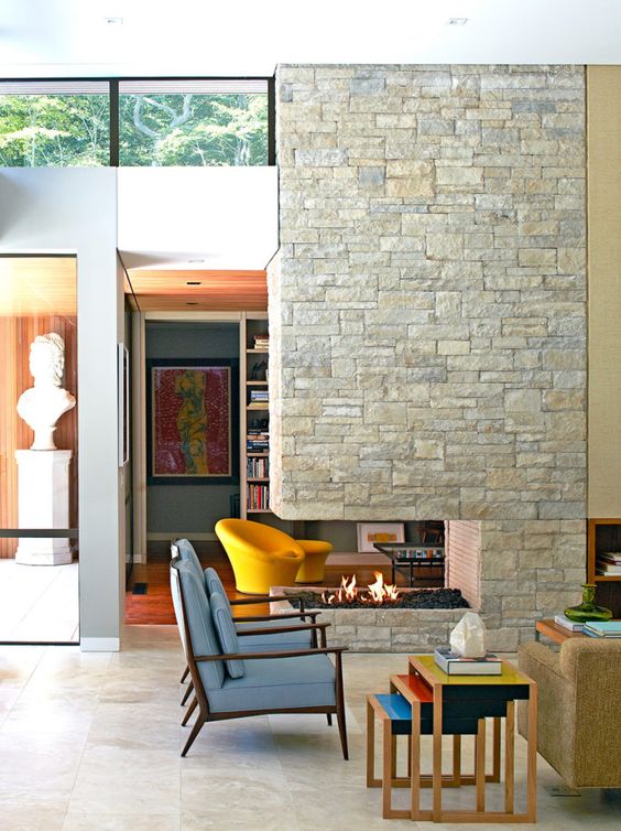 a stone clad double-sided fireplace is a perfect fit for a mid-century modern room