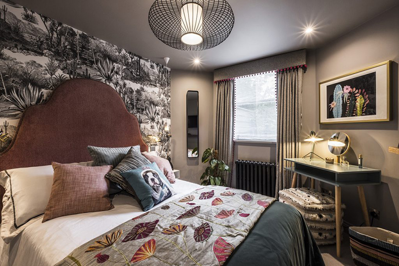The guest bedroom features a black and white botanical print wall, printed textiles and modern furniture