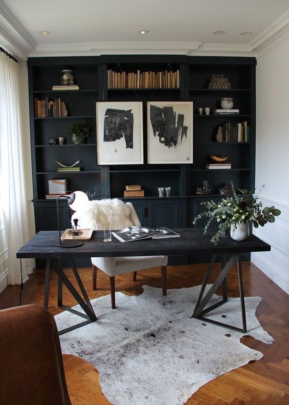 a cozy home office with a black shelving unit that takes a whole wall, an amber-colored wooden floor