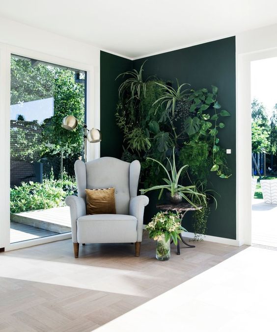 an awkward nook with a living wall, a comfy chair and a table, lots of greenery, it looks very inspiring and refreshing