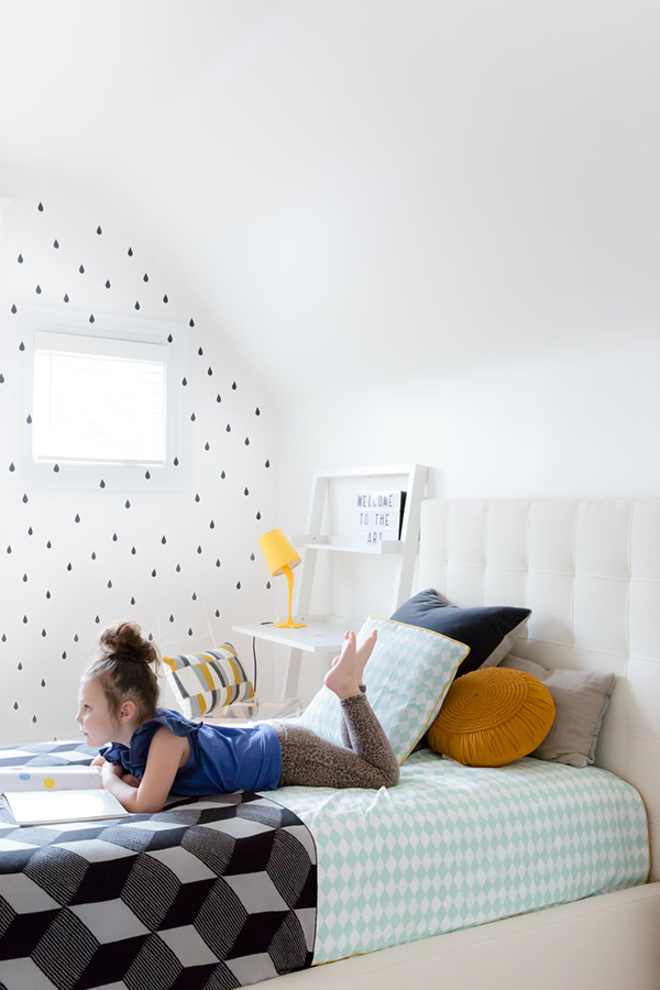 The kid's room features pretty printed wallpaper on one of the walls and some geometric details