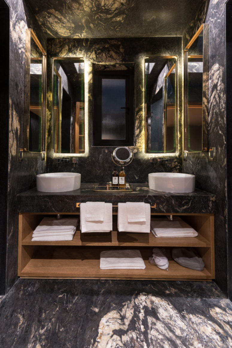 The master bathroom is done in black marble, with lit up mirrors and a double vanity with storage