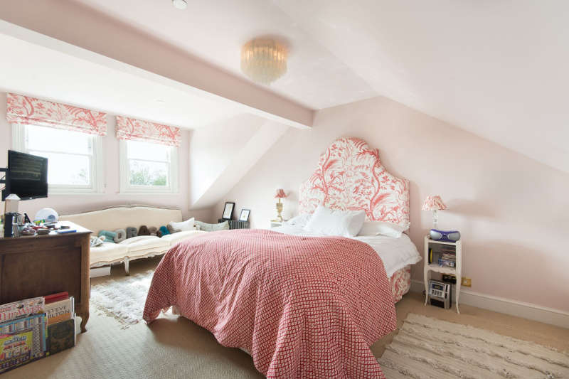 This is a guest bedroom done with the shades of pink and floral prints, the bed is upholstered and the Roman shades are matching ones