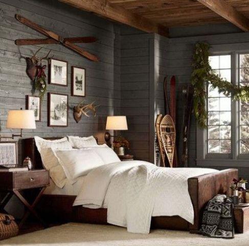 a chalet bedroom with a grey wooden wall, anlers and skis for a cozy feel