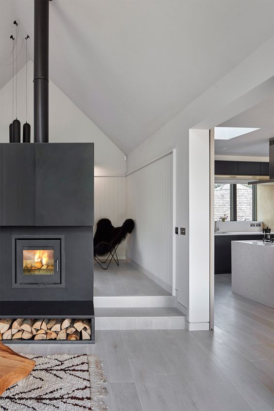 a hearth clad with dark metal makes a bold statement in this open layout and it's visible from all sides
