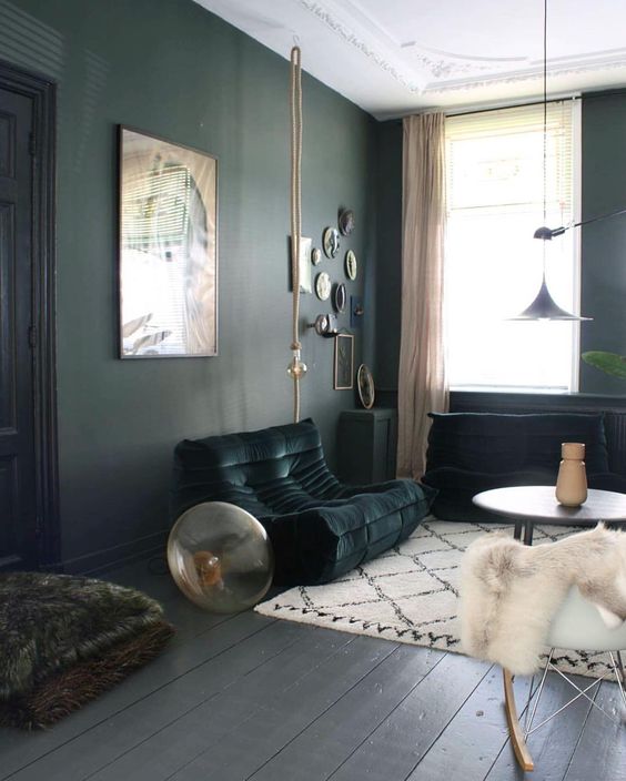 a living room with black walls and furniture, blush textiles and faux fur for a soft contrast and a more interesting look