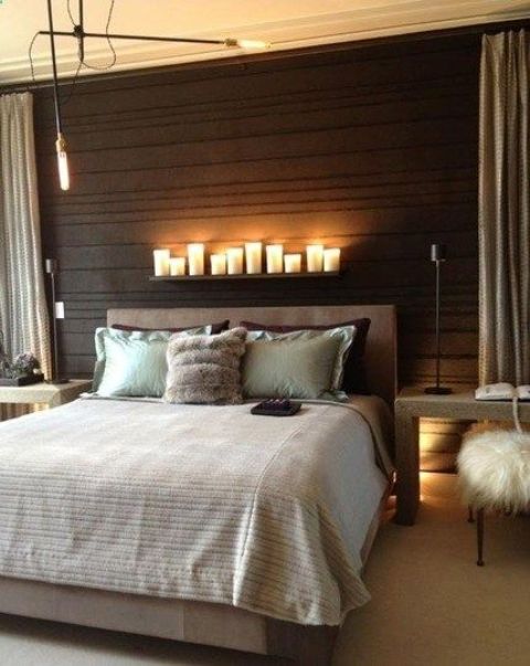 a wood clad black headboard wall is highlighted with a row of candles on a ledge