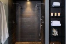 11 large scale black tiles on the walls and floor and some grey touches for a modern dark bathroom