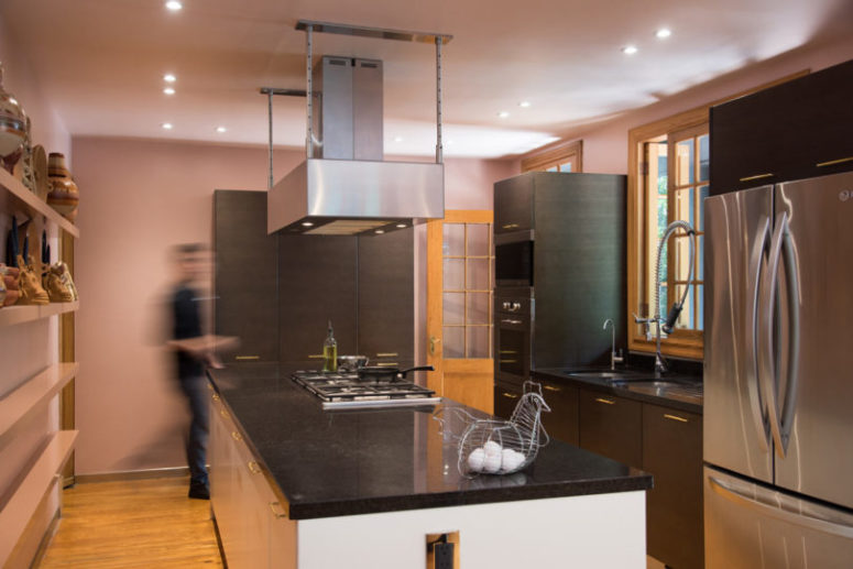 The kitchen is done with pink walls, dark topped furniture, lamps all around and looks very modern