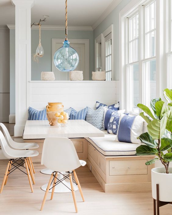 a wooden corner bench with storage space and lots of pillows for a cozy breakfast nook