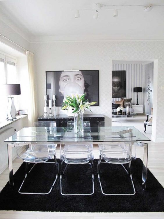 a cool dining table with shiny metal legs and a glass tabletop plus acrylic chairs look not bulky