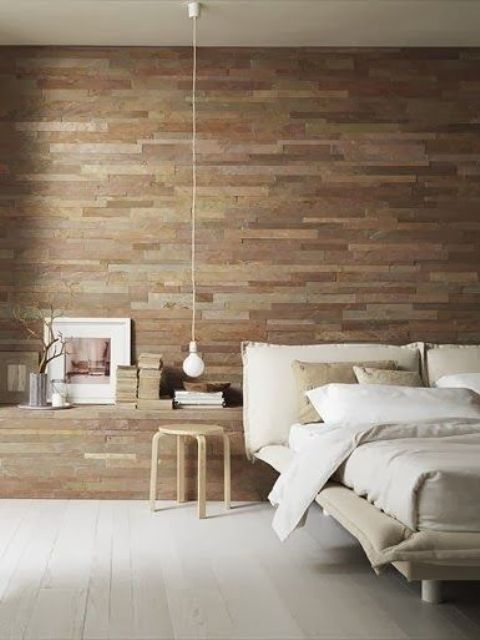 a modern bedroom is made cozier and more welcoming with a reclaimed wooden wall, whitewashed floor and wooden furniture