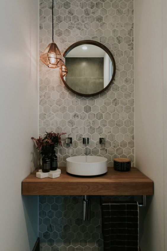 an accent wall with marble hexagon tiles and a wooden vanity make the space eye-catchy