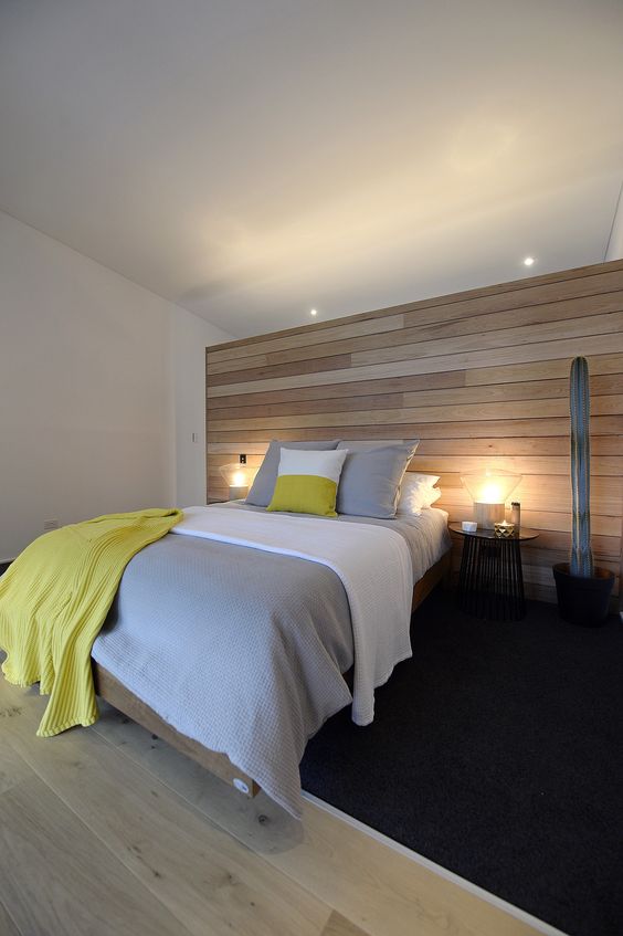 a modern bedroom is completed with a light-colored wooden wall and matching floor