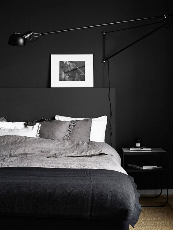 a Scandinavian masculine bedroom with a black wall, bed and bedding looks inviting and relaxing