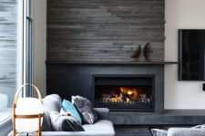 17 a fireplace clad with grey patterned tiles and reclaimed wood over it to keep it safe