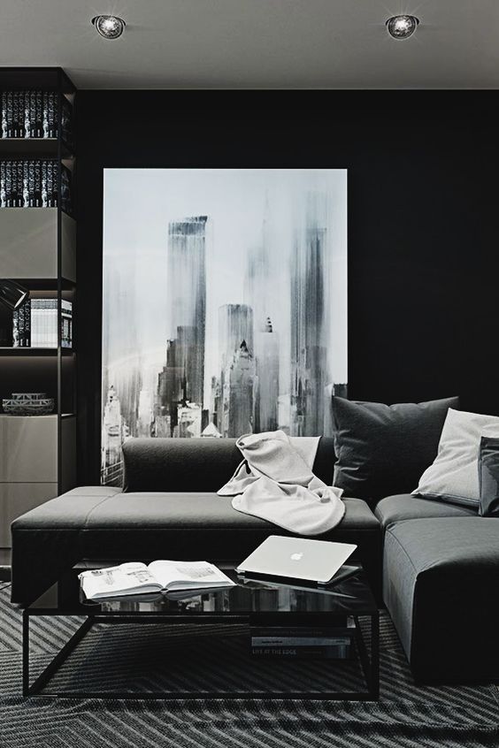 a modern moody space with a corner sofa, a small elegant coffee table, a large graphic artwork and matching textiles