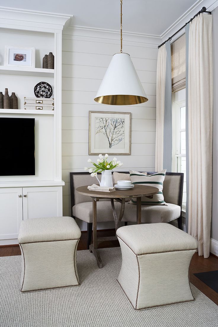 a quiet corner with a small breakfast area, a curved sofa and upholstered poufs, a lamp to highlight the space