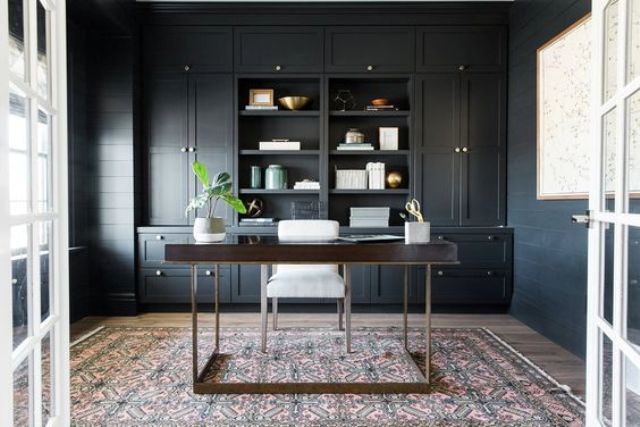 a chic home office space with black walls, and one wall taken with cabinets and shelving, lots of light in